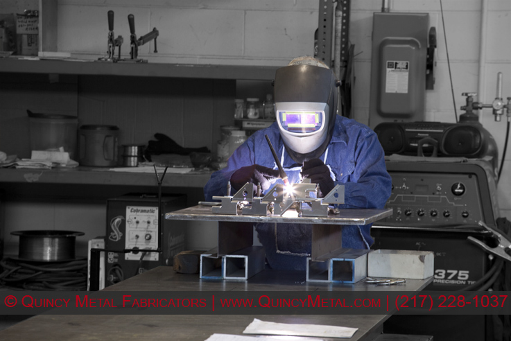 A photo of a welder in Quincy Metal Fabricators' welding department.